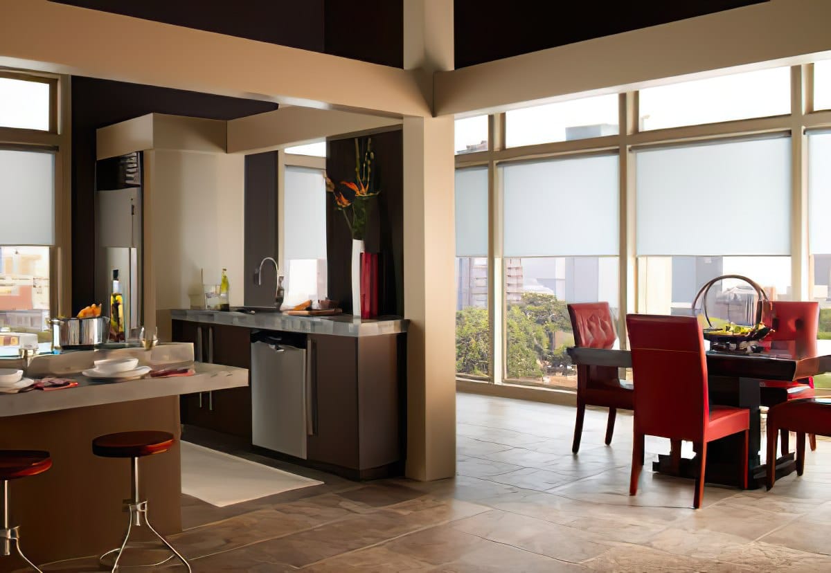 A kitchen and dining room with automatic roller shades by Architectural Window Treatments in a luxurious apartment.